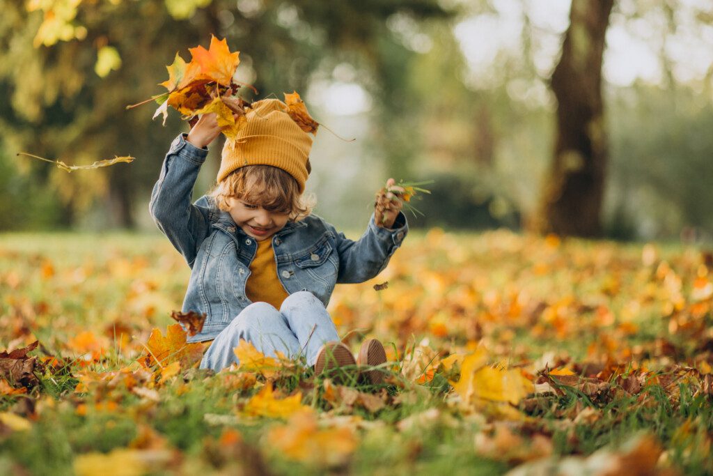 boy-playing-with-leaves-autumn-park-